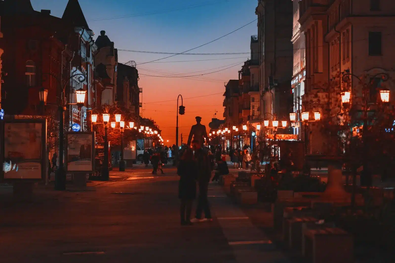 Alignement de pots lumineux délimitant une rue piétonne en soirée d'automne